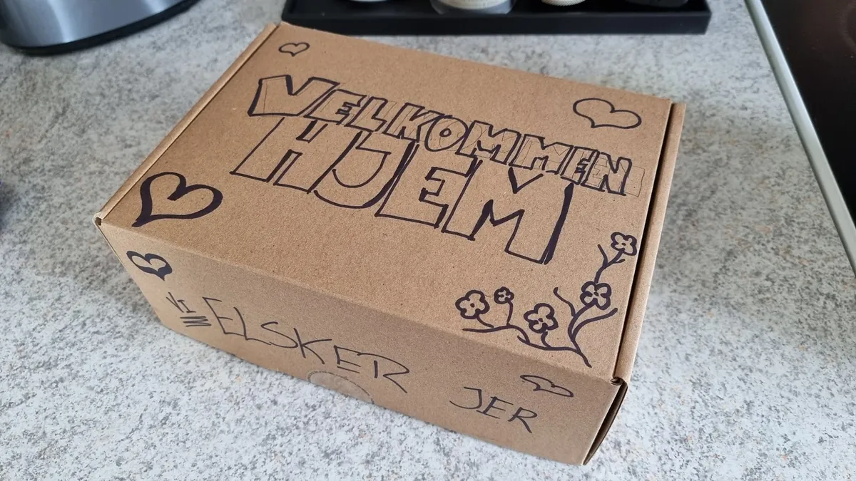 Skattekiste til en skattejagt: en papkasse tegnet på i hånden med Velkommen hjem, hjerter og blomster